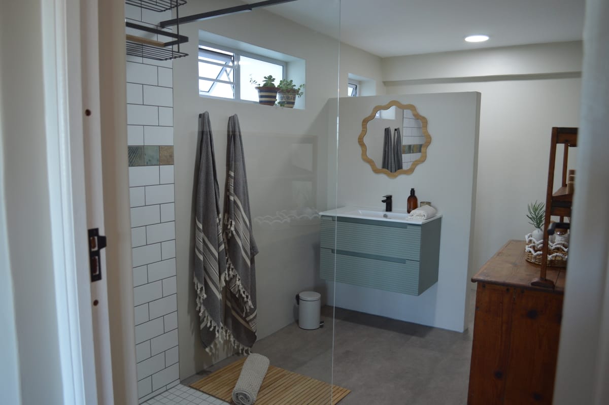 The bathroom, with white metro tiling, a walk-in shower and a sage vanity