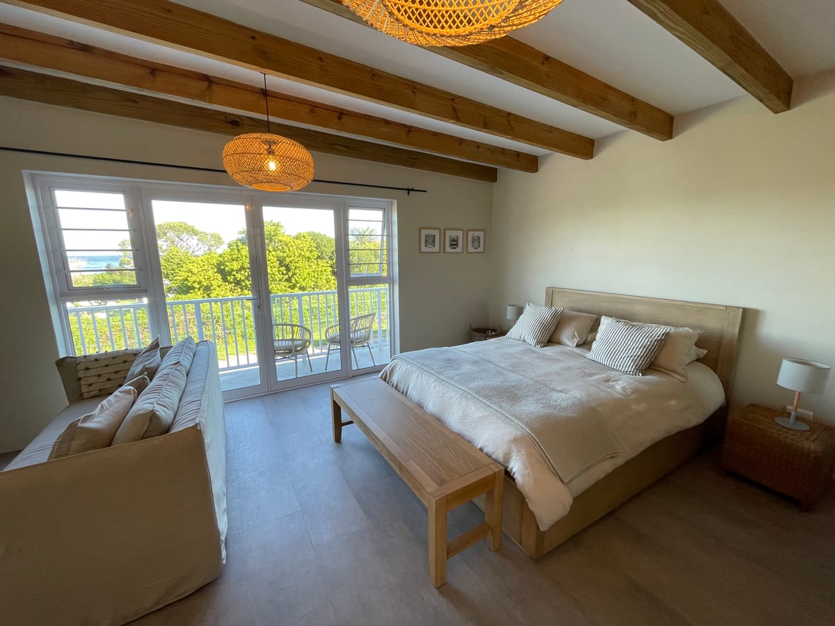 The extra-length queen bed with French doors open onto the balcony chairs