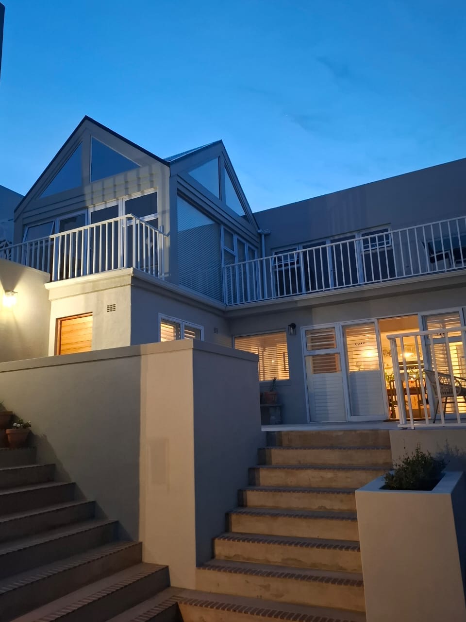 The house at dusk, windows lit above the steps to the private entrance