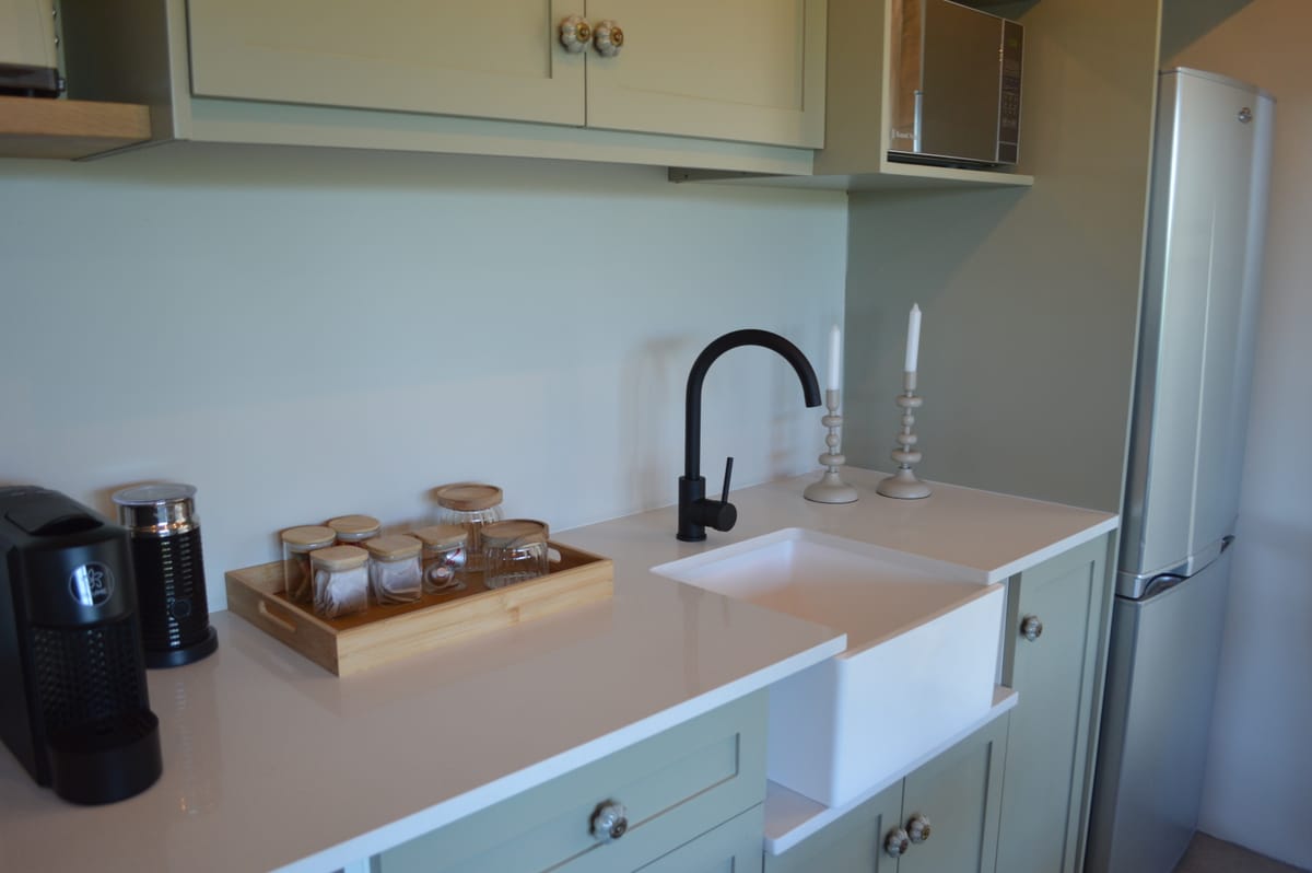 Capsule coffee machine, canisters on a wooden tray and a matte black tap